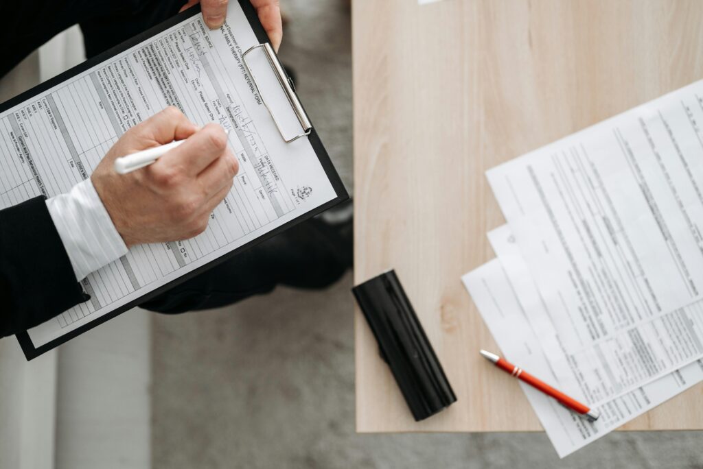 Rapport final High-angle view of a person filling out forms on a clipboard, emphasizing paperwork and documentation.